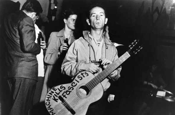 Because his hero was Woody Guthrie