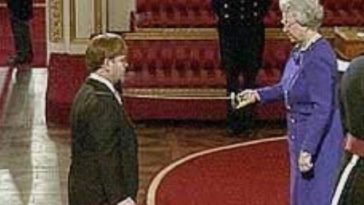 February 24, 1998 - England's Queen Elizabeth II knighted Elton John during a ceremony at Buckingham Palace