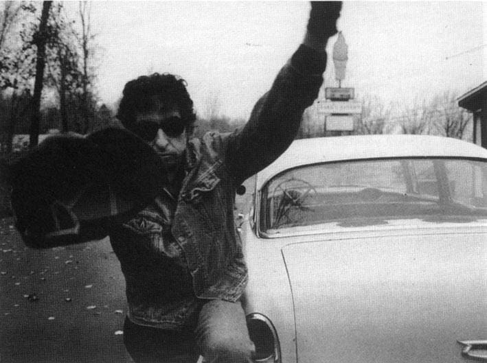 Bob Dylan using his hat to pretend to avoid a photograph, in 1991.  